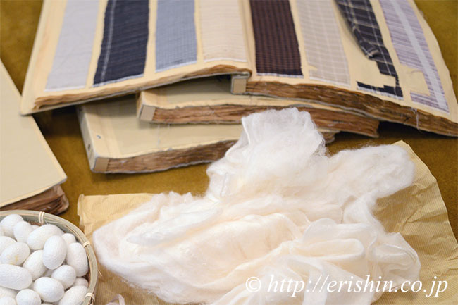 結城紬の縞帳。手前は、繭を広げた真綿。