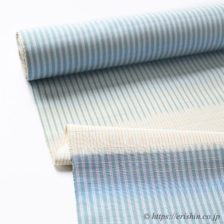 芝崎圭一　座繰紬（絣・多色暈し段/鳥の子色に薄花色のさざ波段）「着物と帯・呉服えり新」